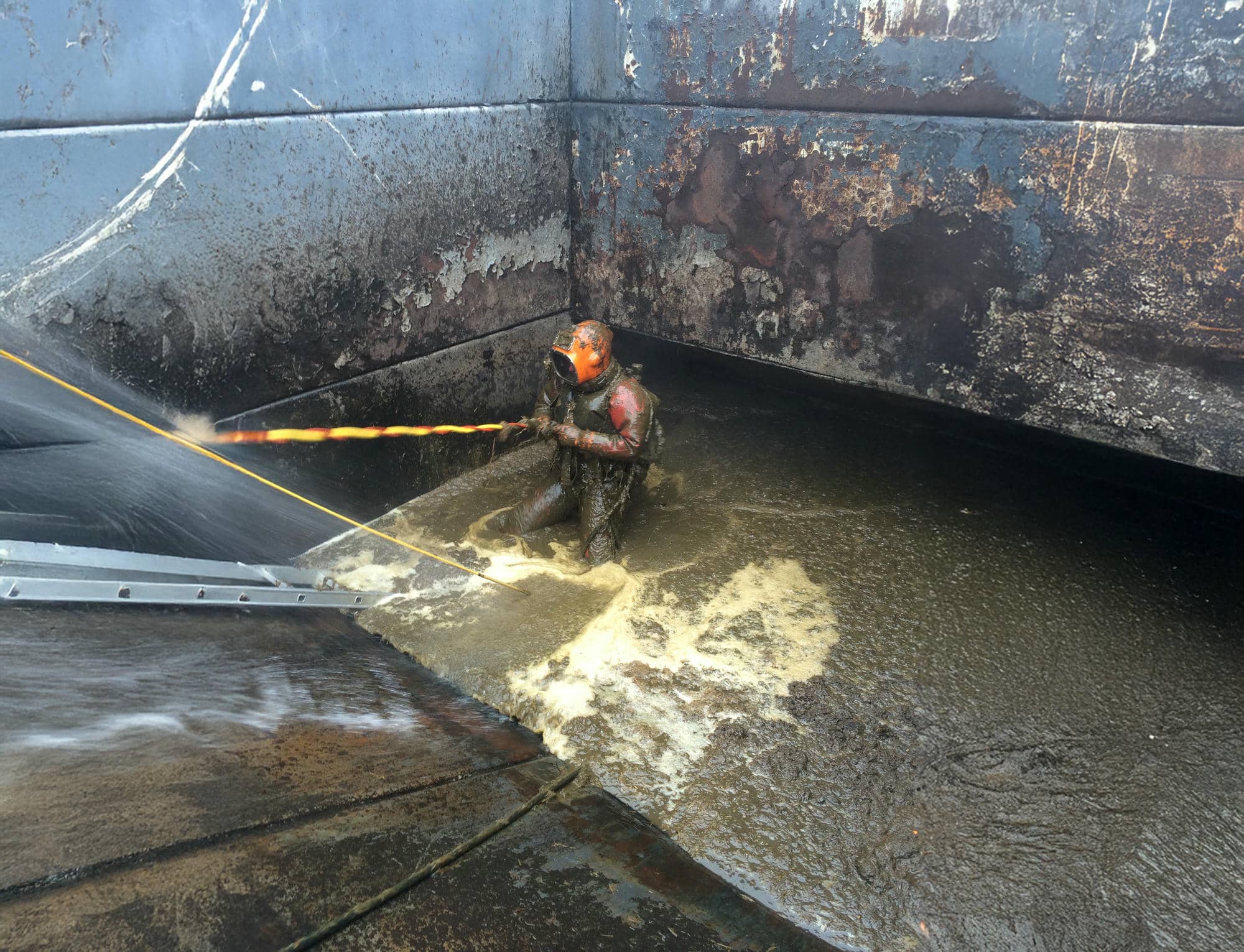Berufstaucher bei Wartungsarbeiten in einer Kläranlage – Reinigung und Instandhaltung unter kontaminierten Bedingungen mit geschlossener Schutzausrüstung und Hochdrucktechnik.